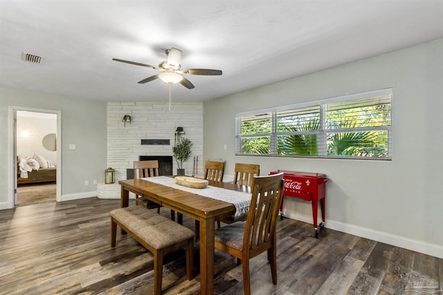 dining room featuring dark hardwood / wood-style floors, ceiling fan, and a fireplace