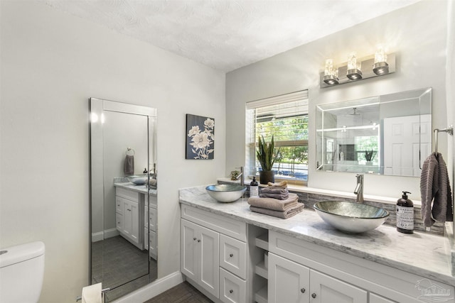 bathroom featuring walk in shower, vanity, toilet, and a textured ceiling