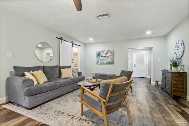 living room with a barn door and dark hardwood / wood-style flooring