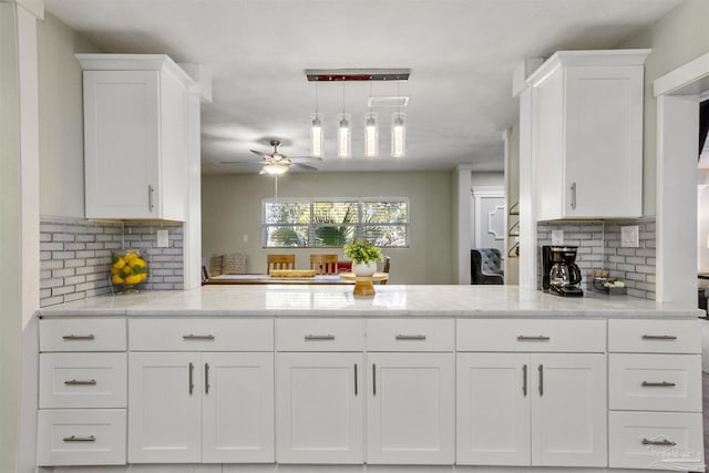 kitchen with tasteful backsplash, pendant lighting, ceiling fan, light stone countertops, and white cabinets