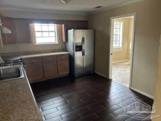 kitchen with stainless steel refrigerator with ice dispenser, dark wood-type flooring, ornamental molding, and sink