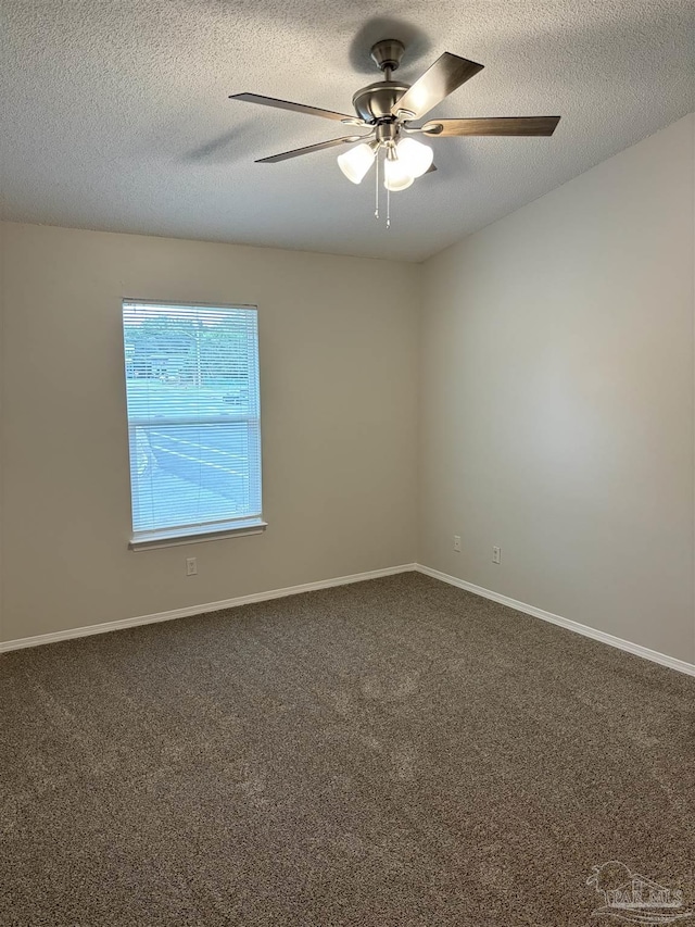 spare room featuring baseboards, ceiling fan, dark carpet, and a textured ceiling