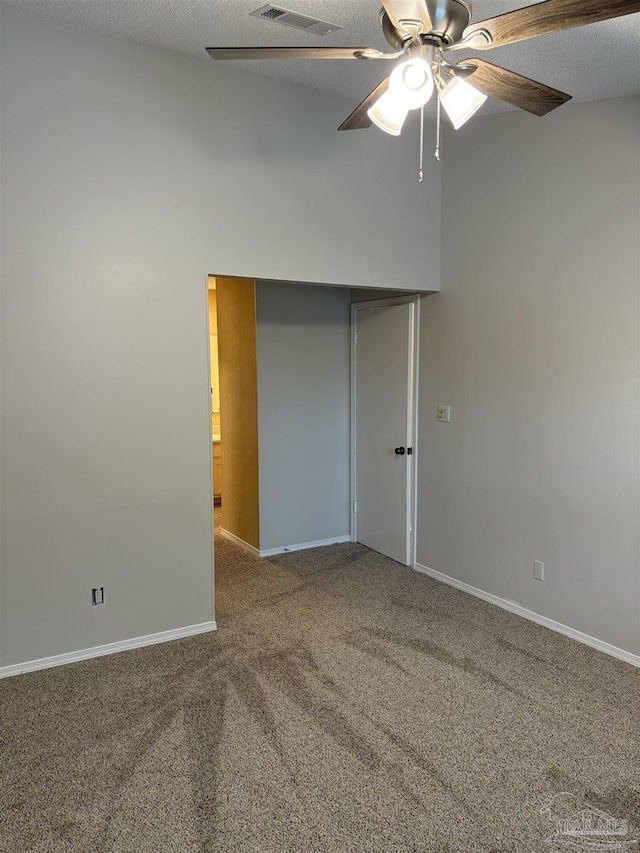 empty room with carpet floors, ceiling fan, visible vents, and baseboards