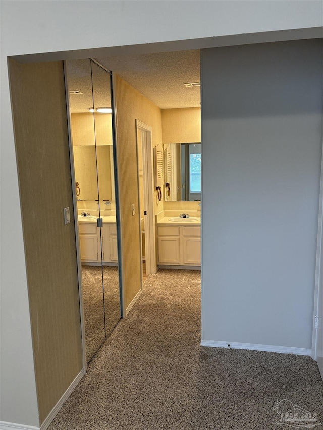hallway with carpet flooring, baseboards, and a sink