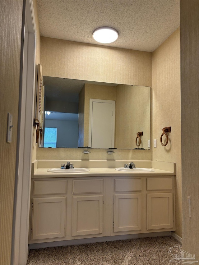 bathroom with double vanity, a textured ceiling, and a sink