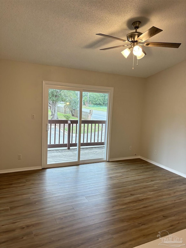 empty room with a ceiling fan, baseboards, dark wood-style floors, and a textured ceiling