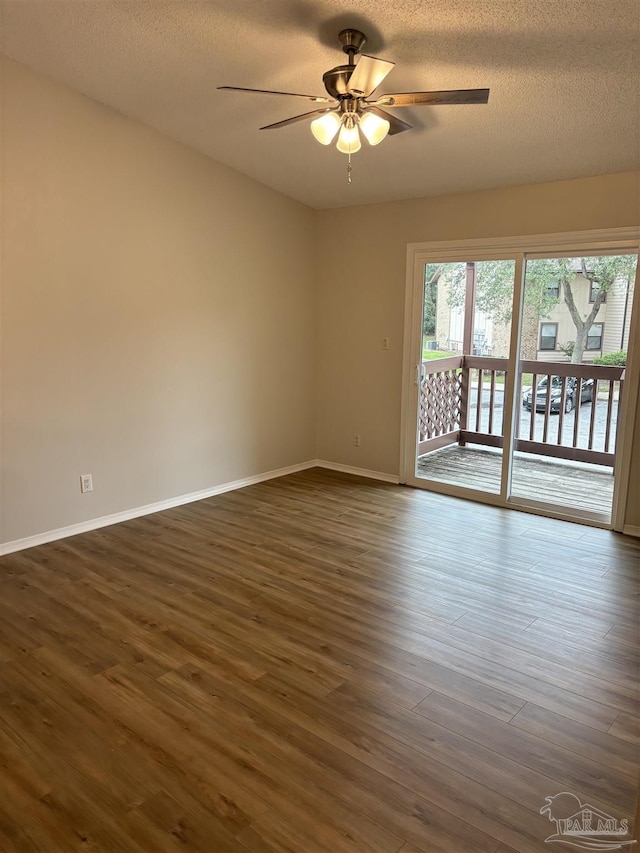 spare room with baseboards, ceiling fan, dark wood-style floors, and a textured ceiling