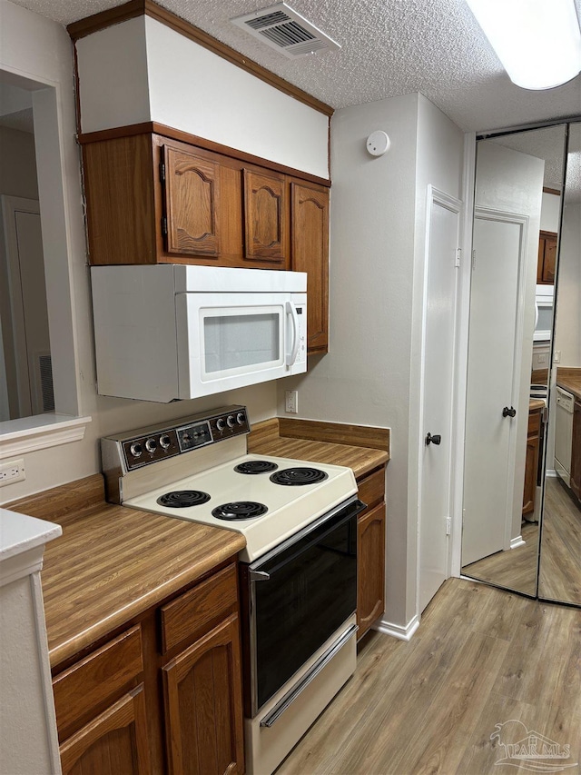 kitchen featuring white appliances, light countertops, a textured ceiling, light wood-type flooring, and visible vents