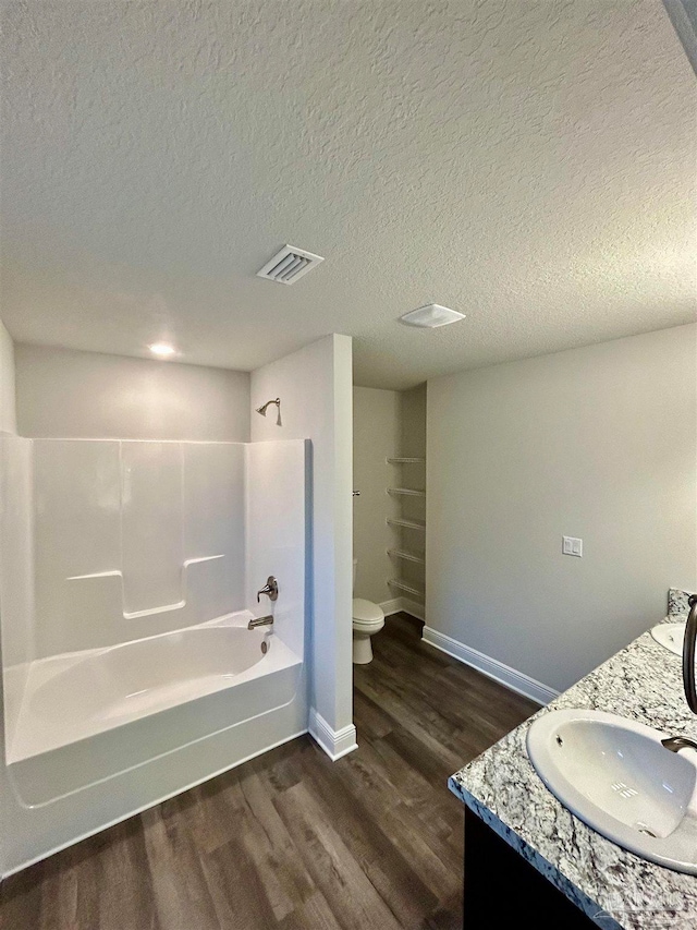 full bathroom featuring vanity, toilet, a textured ceiling, and shower / bathtub combination