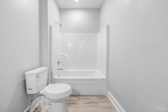 bathroom with hardwood / wood-style flooring, shower / bathtub combination, and toilet