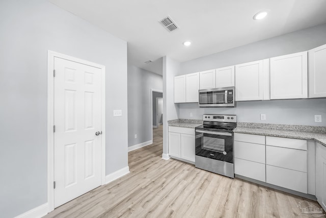 kitchen with light wood-type flooring, white cabinets, and appliances with stainless steel finishes