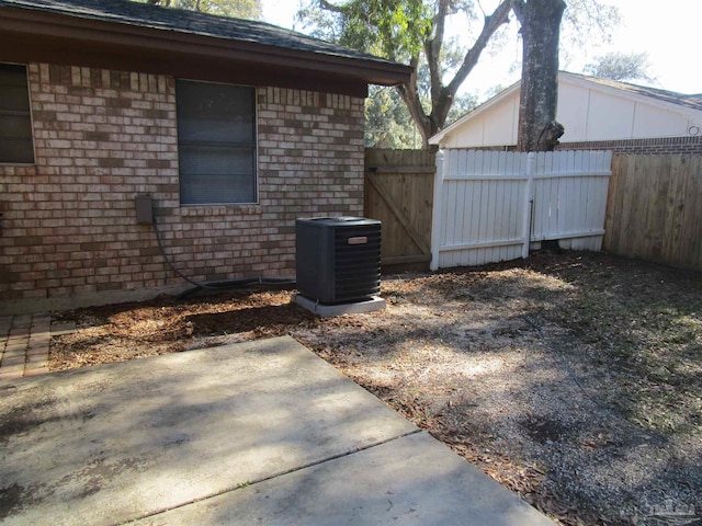 view of property exterior with a patio, fence, cooling unit, and brick siding