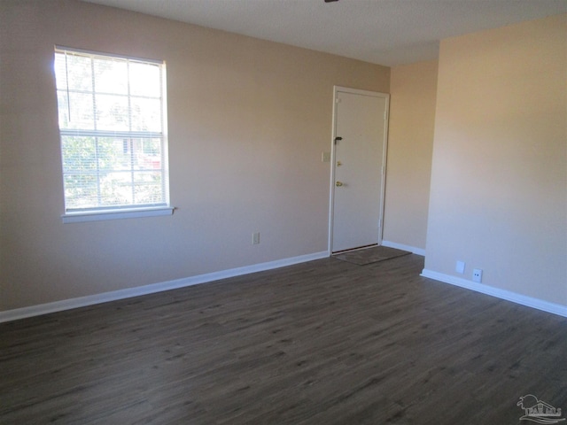 unfurnished room featuring plenty of natural light and dark wood-type flooring