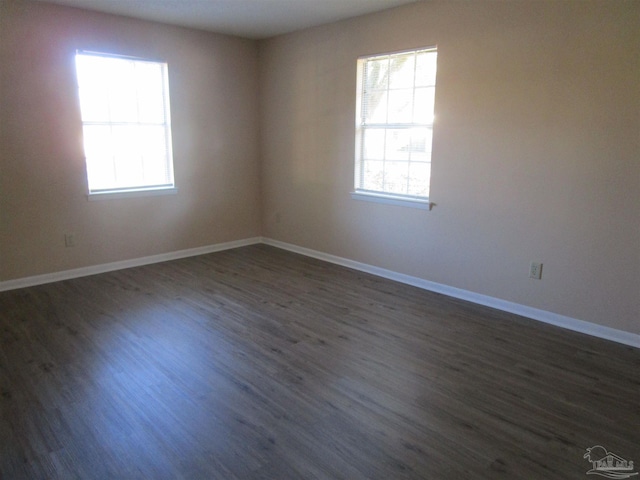 spare room with dark wood-type flooring and baseboards