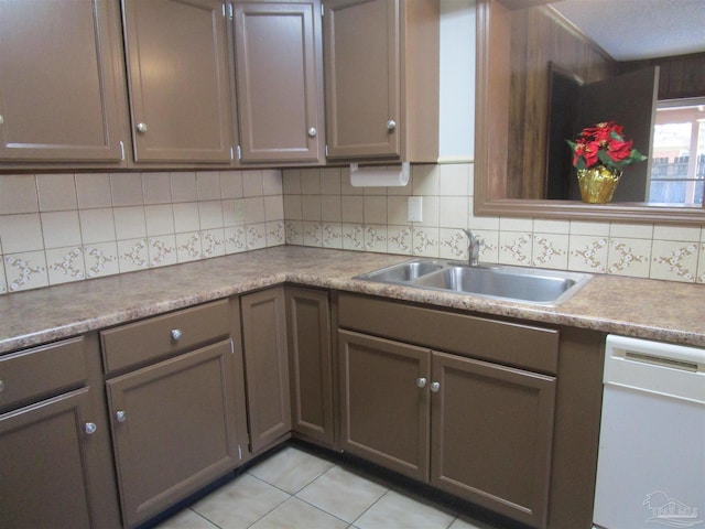 kitchen featuring tasteful backsplash, dishwasher, a sink, and light tile patterned floors