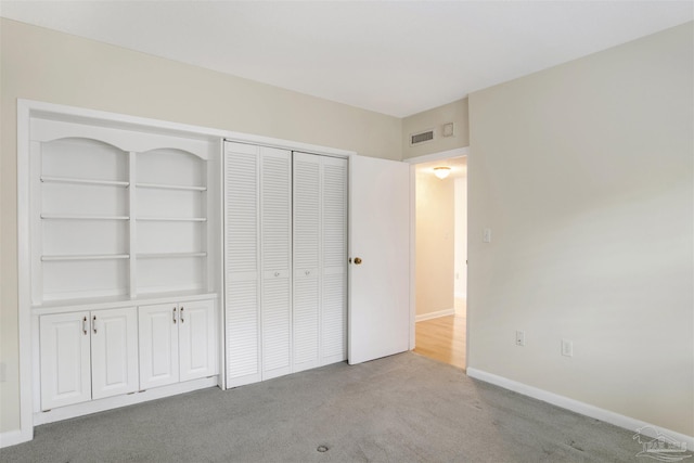 unfurnished bedroom featuring light colored carpet and a closet