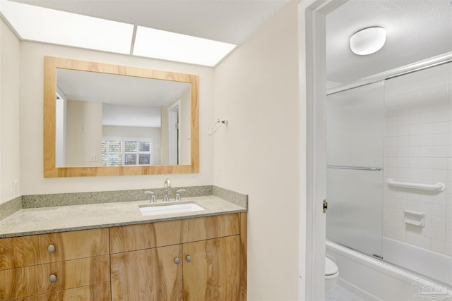 full bathroom with vanity, shower / bath combination with glass door, and toilet