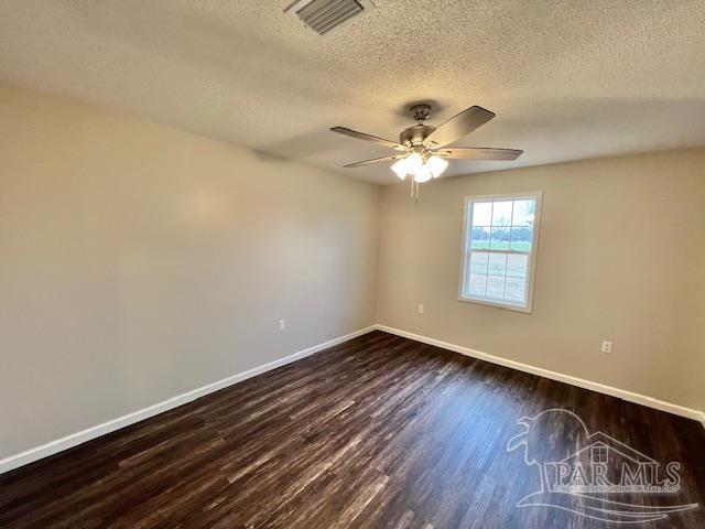 unfurnished room featuring dark wood-type flooring, visible vents, baseboards, and a ceiling fan