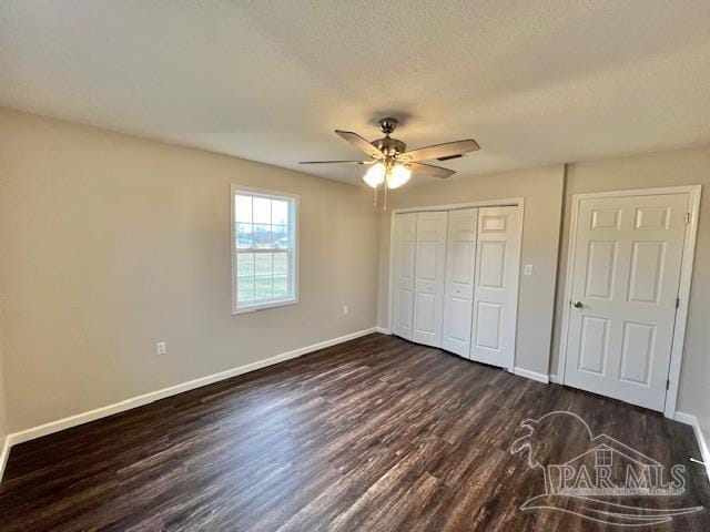 unfurnished bedroom featuring dark wood-style floors, a closet, a ceiling fan, a textured ceiling, and baseboards