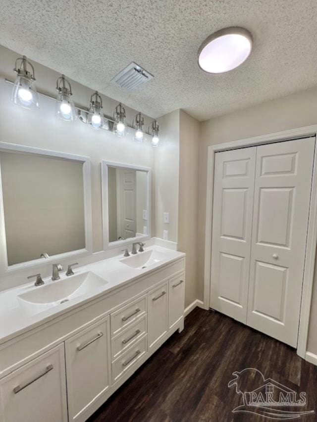 bathroom featuring a closet, visible vents, a sink, and wood finished floors