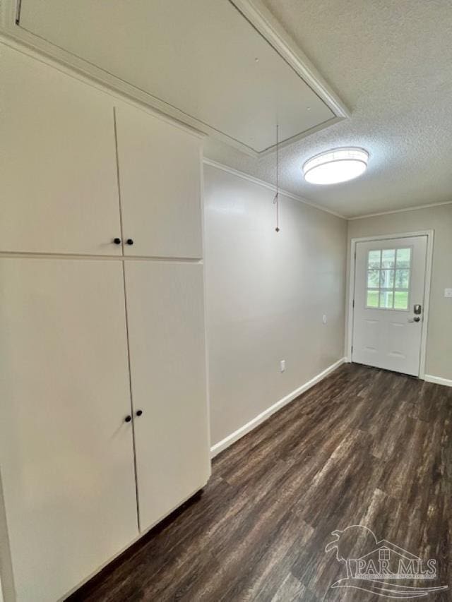 interior space featuring crown molding, dark wood finished floors, a textured ceiling, and baseboards