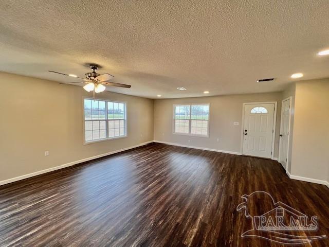 unfurnished living room with dark hardwood / wood-style floors, ceiling fan, and a textured ceiling