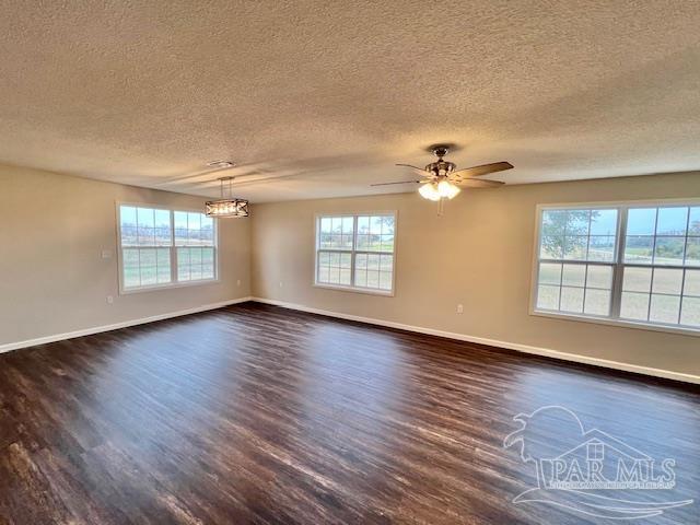 unfurnished room with ceiling fan, plenty of natural light, baseboards, and dark wood finished floors