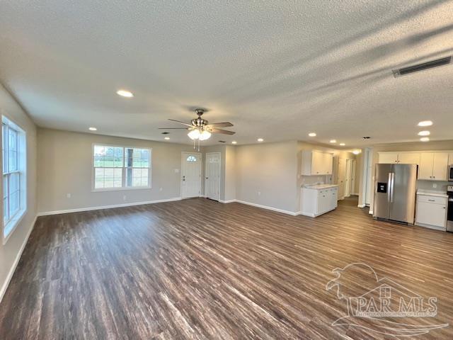 unfurnished living room with dark wood-style floors, baseboards, visible vents, and recessed lighting