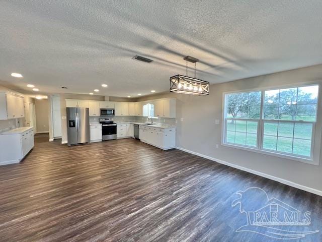 kitchen with visible vents, white cabinetry, open floor plan, light countertops, and appliances with stainless steel finishes