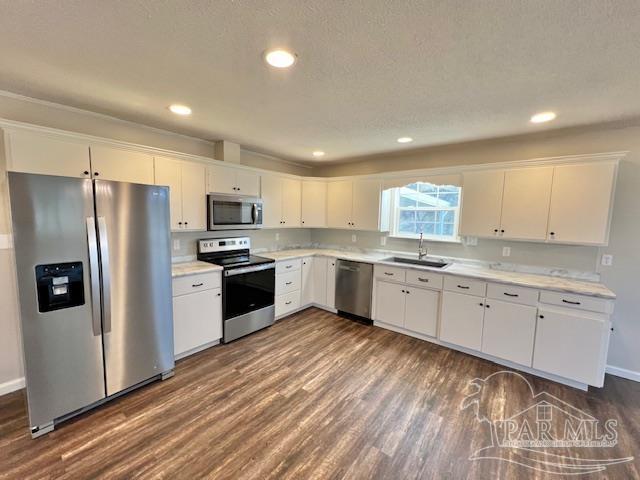 kitchen featuring stainless steel appliances, light countertops, a sink, and white cabinetry