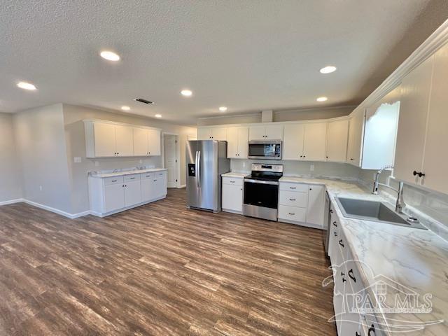 kitchen featuring a sink, stainless steel appliances, dark wood finished floors, and white cabinets