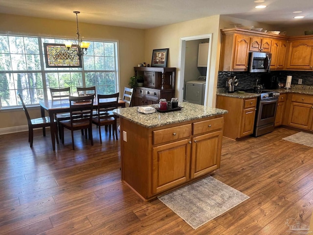 kitchen featuring hanging light fixtures, stainless steel appliances, dark wood-type flooring, an inviting chandelier, and washer / clothes dryer