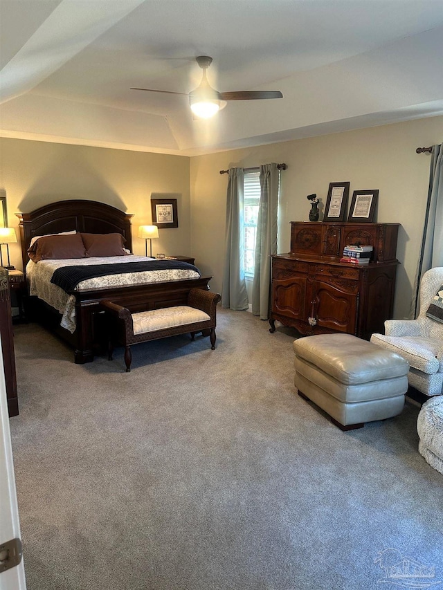 carpeted bedroom with a tray ceiling and ceiling fan