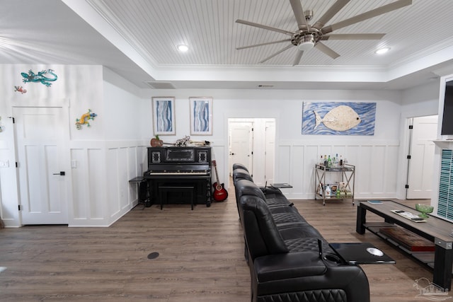 living room featuring a tray ceiling, ceiling fan, dark wood-type flooring, and ornamental molding