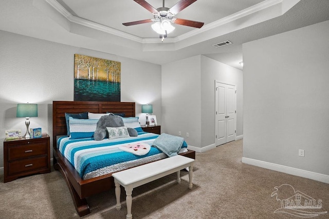 carpeted bedroom featuring a tray ceiling, ornamental molding, baseboards, and ceiling fan