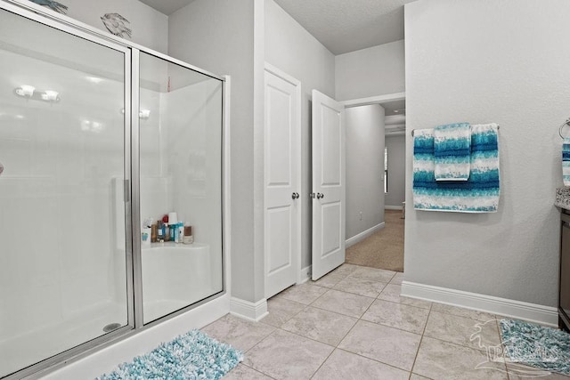 full bathroom featuring a shower stall, baseboards, and tile patterned flooring