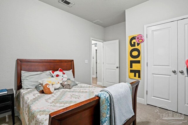 carpeted bedroom featuring baseboards, a textured ceiling, and a closet