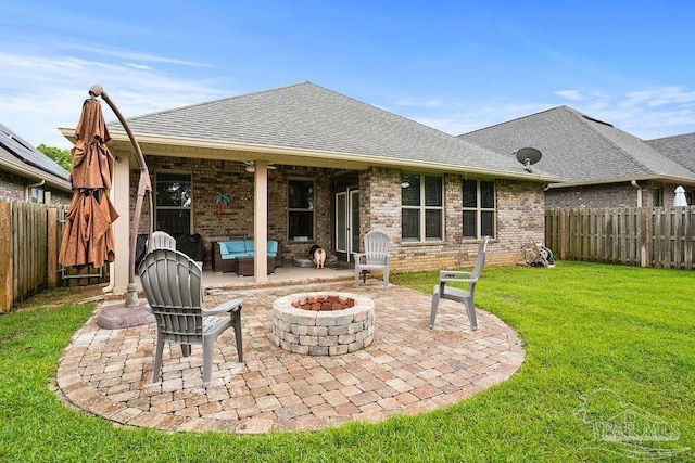rear view of property with a fire pit, a patio, roof with shingles, and brick siding