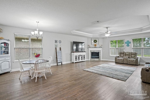 living room featuring wood finished floors, a ceiling fan, baseboards, a chandelier, and a textured ceiling