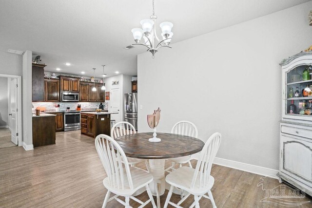 dining room featuring baseboards, light wood-style floors, a chandelier, and recessed lighting
