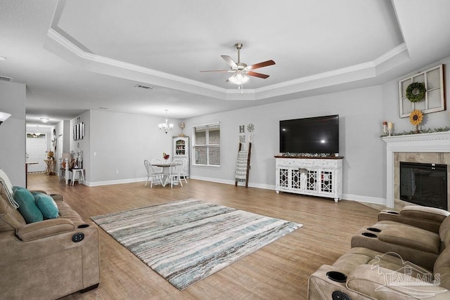 living area featuring a tray ceiling, wood finished floors, a ceiling fan, plenty of natural light, and ornamental molding