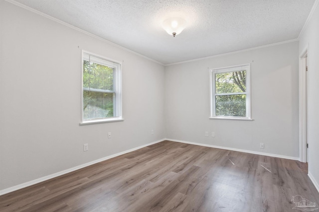 spare room featuring a wealth of natural light, wood finished floors, ornamental molding, and a textured ceiling