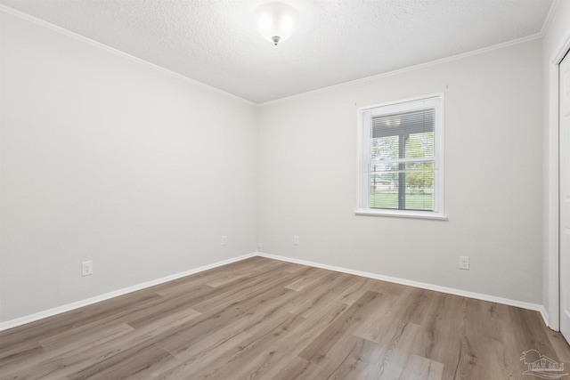 empty room featuring ornamental molding, a textured ceiling, baseboards, and wood finished floors