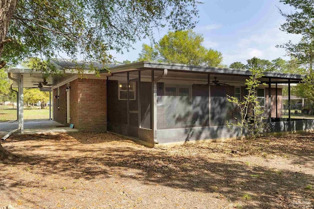 rear view of property featuring a sunroom, brick siding, and a ceiling fan