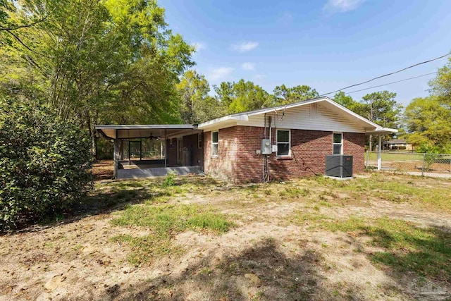 rear view of property featuring a sunroom, fence, brick siding, and central AC