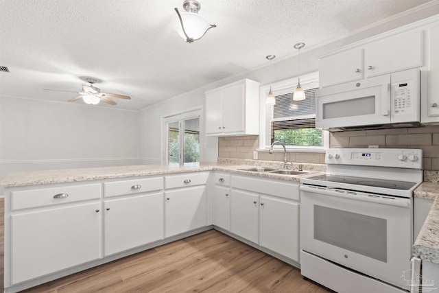 kitchen with light countertops, a sink, light wood finished floors, white appliances, and ceiling fan