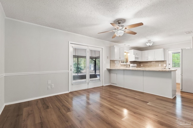 kitchen with crown molding, backsplash, white cabinetry, wood finished floors, and ceiling fan