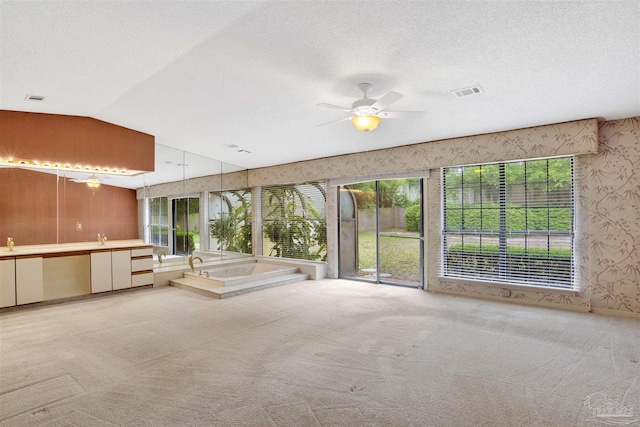 unfurnished living room featuring visible vents, carpet, lofted ceiling, wallpapered walls, and a ceiling fan