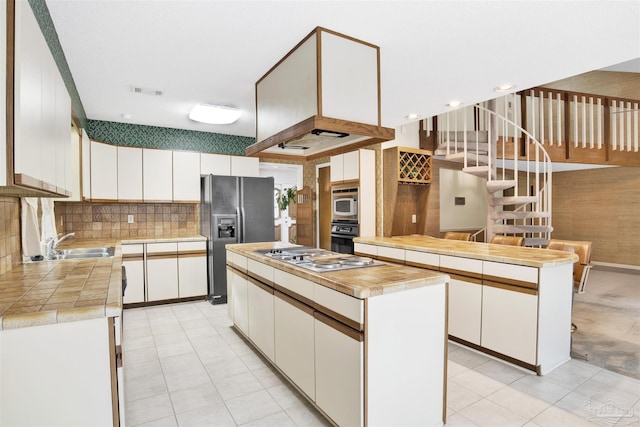 kitchen featuring a sink, stainless steel appliances, backsplash, white cabinetry, and a kitchen island
