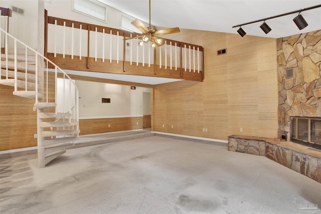 unfurnished living room featuring rail lighting, visible vents, a ceiling fan, a fireplace, and stairs